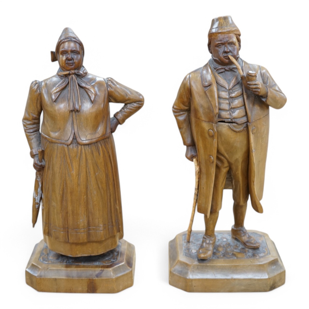 A pair of 19th century Black Forest figural tobacco jars, one of a gentleman with a stick smoking a pipe, the other of a lady holding an umbrella, gentleman 35cm high. Condition - damage to gents front waitcoat, back bow